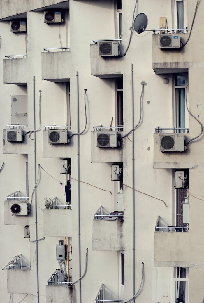 Vertical view of modern apartments with balconies featuring air conditioning units.